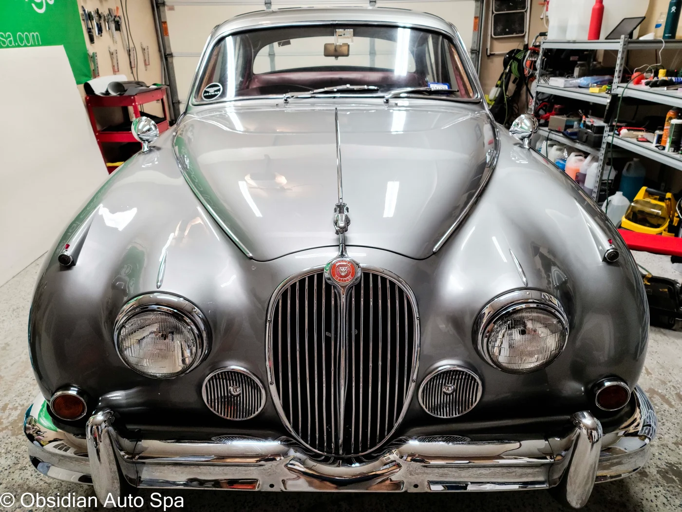 Front view of a silver classic Jaguar in the garage